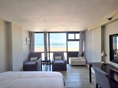 Un dormitorio con una cama y dos sillas y una mesa. en Oceanfront Studio 2 Queen beds kitchenette & pool, en Daytona Beach