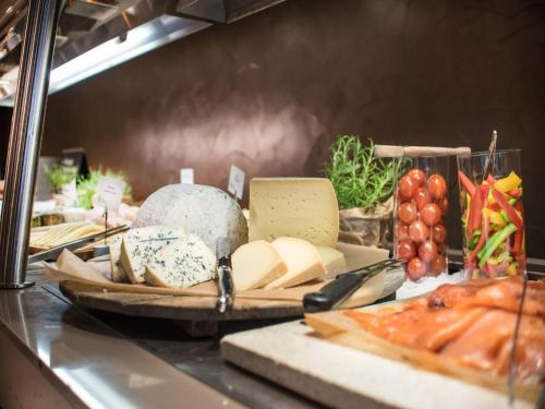 a counter with cheese and other food items on it at Radisson Blu Hotel Leipzig in Leipzig