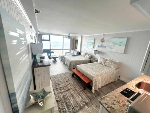una habitación de hotel con dos camas y un sofá en Sunrise Oceanfront 2 Full Studio w/kitchen & pool, en Daytona Beach