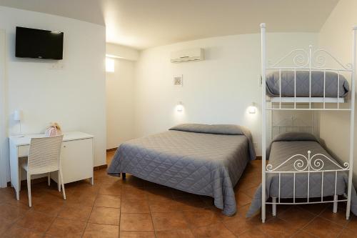 a bedroom with two beds and a desk and a television at Il Geranio - Resort & Suites in Acquedolci