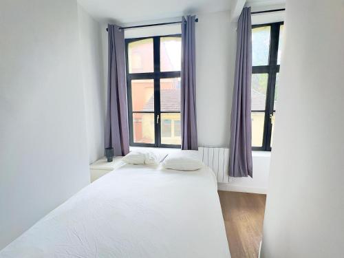 - un lit dans une chambre avec 2 fenêtres dans l'établissement Cosy appart- 4 pers Netflix Hyper centre Douai, à Douai