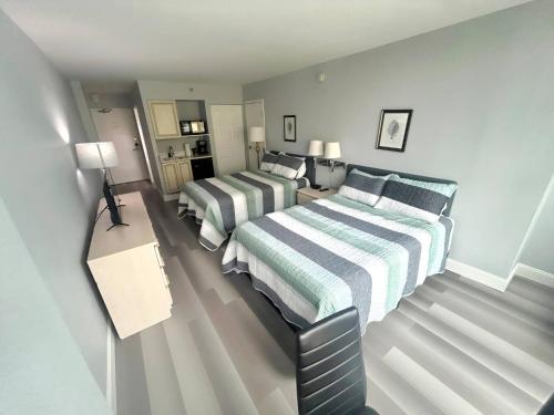 a bedroom with two beds and a table with lamps at Oceanview Studio w/kitchen, pool, tiki bar in Daytona Beach