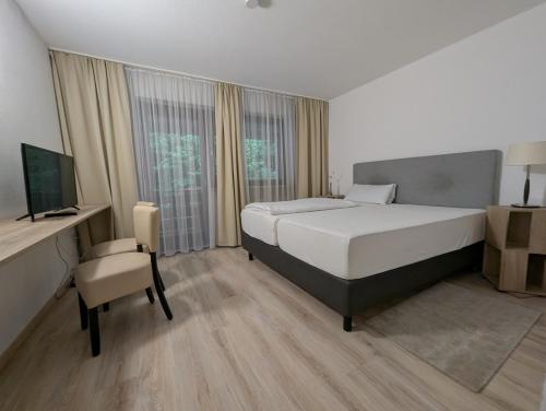 a bedroom with a bed and a desk and a television at Hotel Pension Blüchersruh in Bad Berneck im Fichtelgebirge