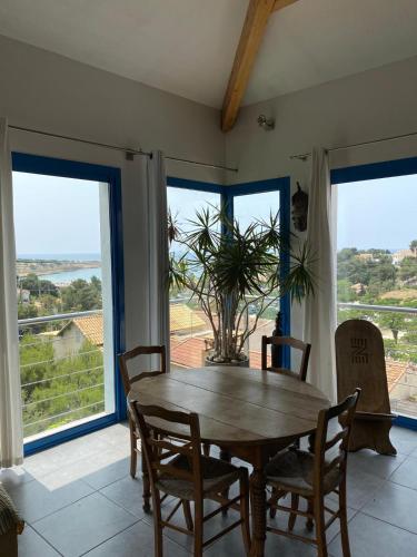 une salle à manger avec une table, des chaises et des fenêtres dans l'établissement Le Loft, à Martigues
