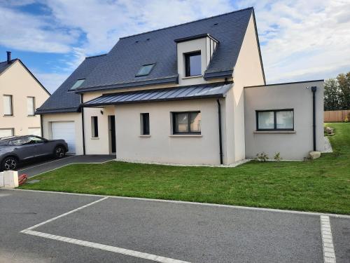 ein weißes Haus mit einem schwarzen Dach in der Unterkunft Maison 6 personnes in Saint-Méloir-des-Ondes