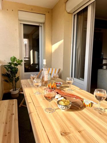 - une longue table en bois avec des verres à vin dans l'établissement Plage à 15 min - Proche de la Gare - 6 personnes - 3 Chambres - Idéal Famille, à Narbonne