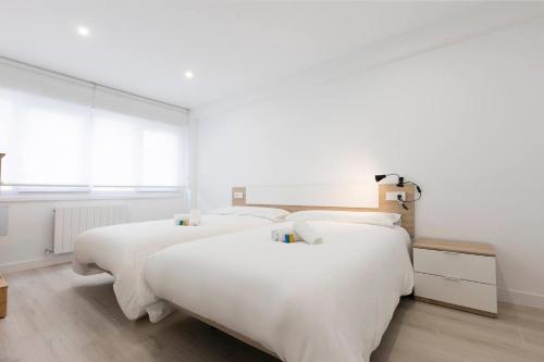 two beds with white sheets in a bedroom at Apartamento Hondarribia centro in Hondarribia