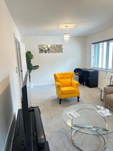a living room with a yellow chair and a tv at Luxury four bedroom house in Wolverhampton