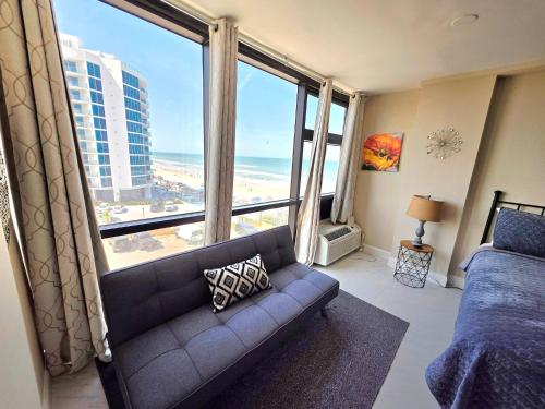 a living room with a couch and a view of the ocean at 2 queen bed studio w/kitchenette, pool, tiki bar in Daytona Beach