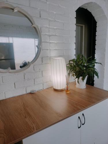 a table with a lamp and a mirror on it at Stay at Percy2 in Nelspruit