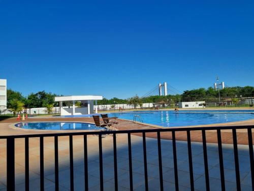 una grande piscina con due sedie e una recinzione di Apto versátio trabalho e lazer a Cuiabá