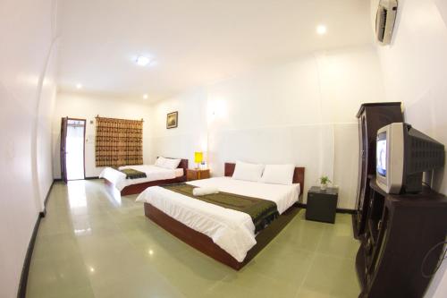 a bedroom with two beds and a tv in it at RS Guesthouse in Phnom Penh