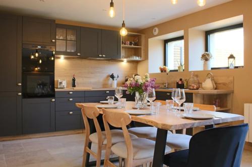 une cuisine avec une table en bois et des chaises ainsi qu'une salle à manger dans l'établissement L'Écurie - Nature et SPA privé, à Béganne