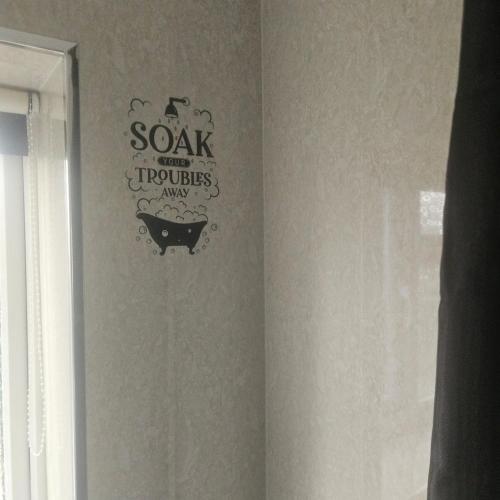 a bathroom with a bath tub with a sign on the wall at Spacious 3bed, Sleeps5, Parking in Birmingham