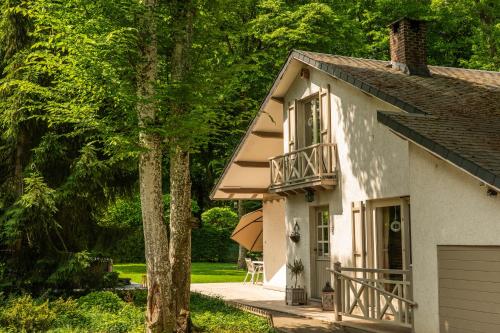 a white house with a balcony and a tree at Le Colibri spa jacuzzi in Durbuy