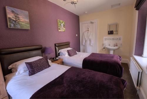 two beds in a room with purple walls at Cornlee in Aysgarth