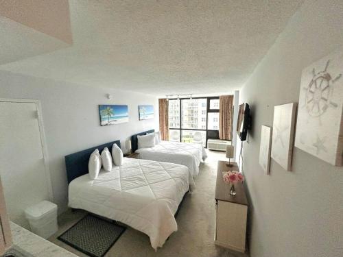 デイトナビーチにあるDaytona Oceanside Adjoin studios w/pool, Tiki Barのベッド2台とテレビのある寝室