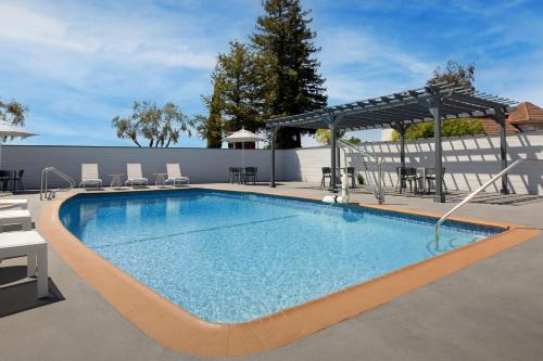 a swimming pool with chairs and a pavilion at Spark by Hilton San Jose Airport in San Jose