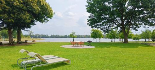 un parco con una panchina e tavoli sull'erba di Ferienwohnung Coproyshof am See in Wesel am Niederrhein 5 Sterne DTV-Klassifizierung 6 Personen a Wesel