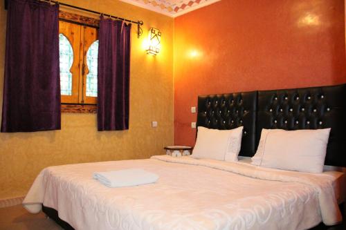 a bedroom with a large bed with white sheets at Dar Diafa Kaltom in Ouzoud