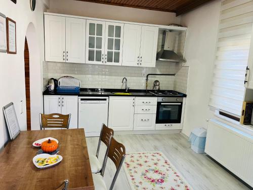a kitchen with white cabinets and a wooden table at Eren Villa in Sapanca