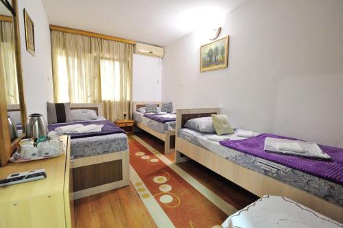 a room with two beds and a table with a desk at Motel Edem in Mostar