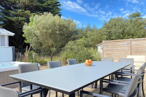 a table and chairs on a patio with trees at Villa Tanzanie - Domaine Le Sherwood in Notre-Dame-de-Monts