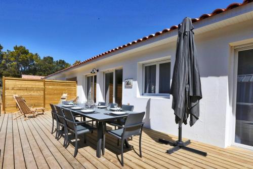 - une table avec des chaises et un parasol sur une terrasse dans l'établissement Villa Tanzanie - Domaine Le Sherwood, à Notre-Dame-de-Monts