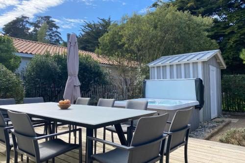 a patio with a table and chairs and a hot tub at Villa Tanzanie - Domaine Le Sherwood in Notre-Dame-de-Monts