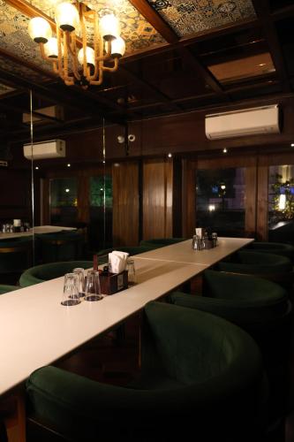 a long table in a restaurant with green chairs at Golden Parkk Hotel in Kolkata