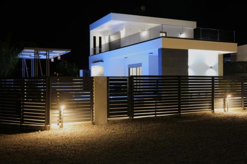 a blue house with a fence in front of it at night at Villa Viventia in Afantou
