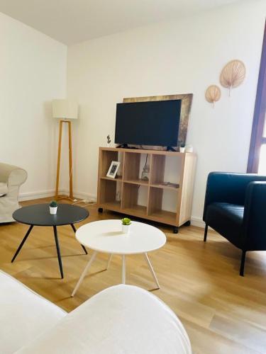 a living room with a tv and a couch and tables at Le Repaire Urbain - 8 voyageurs in Orléans