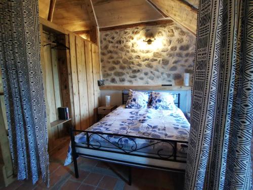 a bedroom with a bed and a stone wall at la pause nature in Saint-Martial