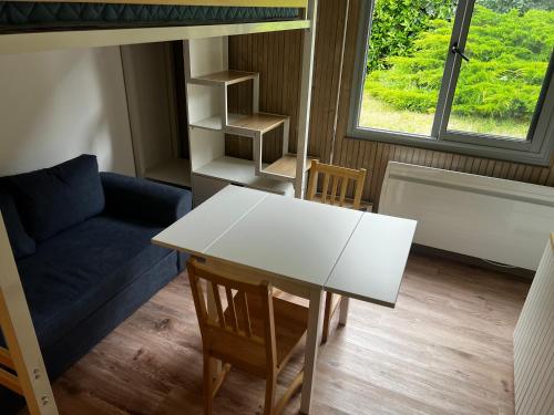 Cette chambre comprend une table, un canapé et une fenêtre. dans l'établissement Jolie studio à 200m de la plage principale, à Arcachon