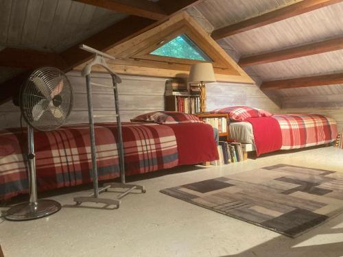 a attic bedroom with two beds and a fan at Holy Wood in Chuelles