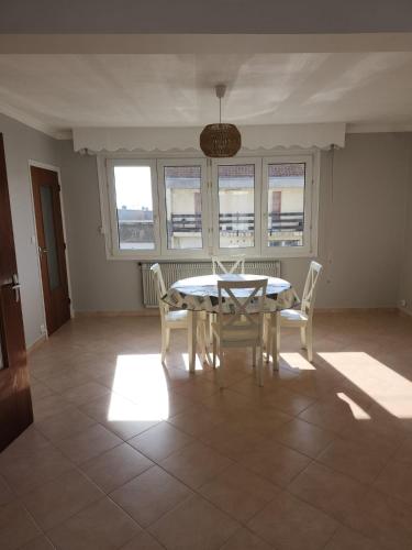 une salle à manger avec une table, des chaises et des fenêtres dans l'établissement La mer, à Le Portel