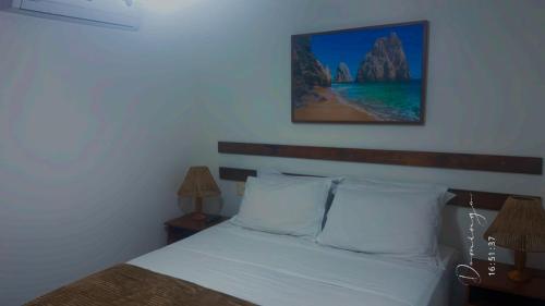 a bedroom with a bed with two lamps and a picture on the wall at Porto Praia do Forte in Praia do Forte