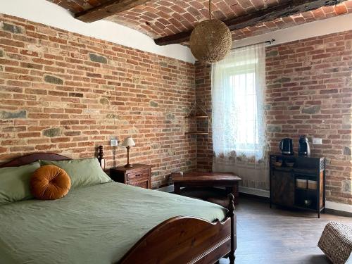 a bedroom with a bed and a brick wall at Cascina Il Girasole Rosso in Cortazzone