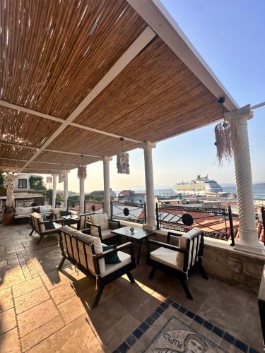 a patio with chairs and tables and a view of the ocean at Villa Ephesus Hotel in Kusadası