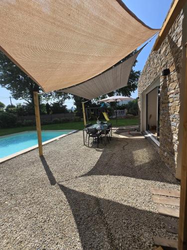 une terrasse avec une table et des chaises sous un grand parasol dans l'établissement Partie privative dans villa 6 personnes piscine climatisé, aux Arcs-sur-Argens