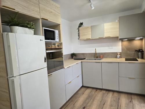 a kitchen with white cabinets and a white refrigerator at Partie privative dans villa 6 personnes piscine climatisé in Les Arcs sur Argens