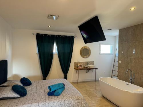 une chambre avec un lit, une baignoire et une télévision dans l'établissement Maison LUMIERE, à Saleilles