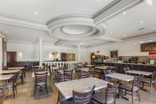 a restaurant with tables and chairs and a bar at Best Western Plus Travel Hotel Toronto Airport in Toronto