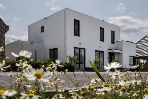 a white house with black windows and white flowers at The White House Apartment in Tholen