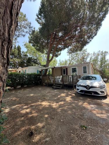 une voiture garée devant une petite maison dans l'établissement Mobil Home 2 chambres Sous les pins, à Torreilles