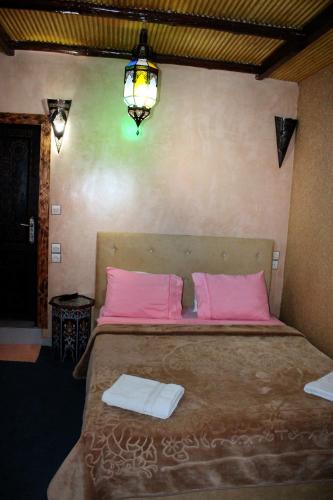 a bedroom with a bed with pink pillows and a light at Dar Diafa Kaltom in Ouzoud