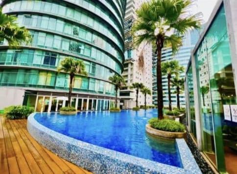 a large building with a large blue pool in front of it at Vortex KLCC by Family Suites in Kuala Lumpur