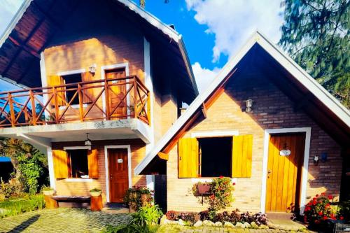 a house with a balcony on the side of it at VELINN Pousadas Flor da Montanha in Monte Verde