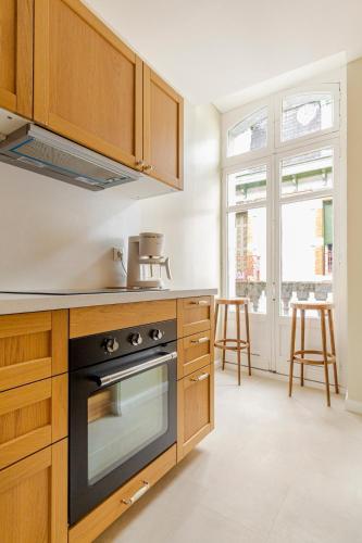 - une cuisine avec des placards en bois et une cuisinière dans l'établissement Magnifique appartement rénové, à Bagnères-de-Bigorre