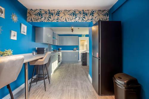 a kitchen with blue walls and a black refrigerator at Room 1, 23 Deganwy Avenue in Llandudno